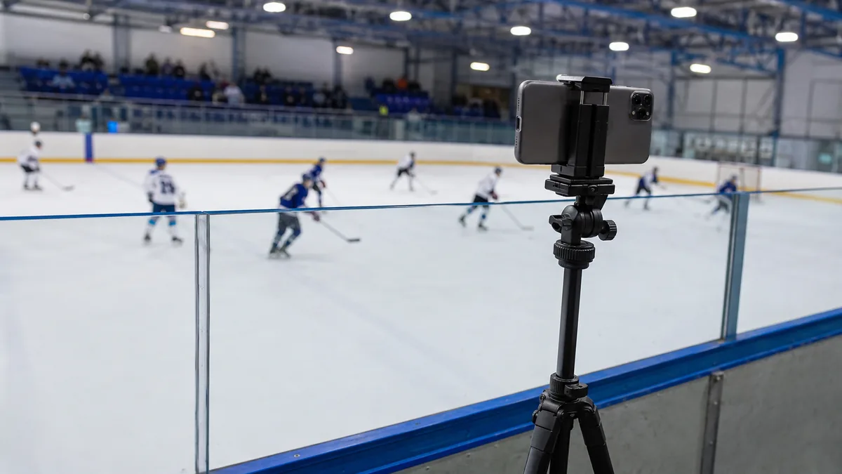 Téléphone sur trépied au-dessus de la balustrade d'une patinoire, match de hockey en cours sur la glace